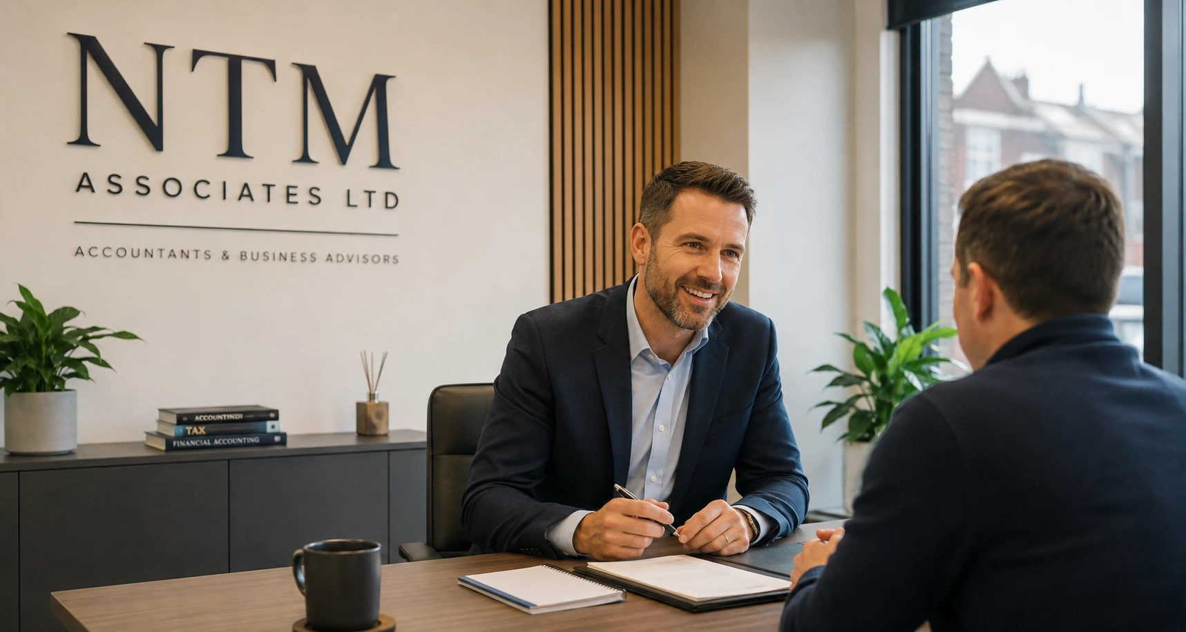 Accountant meeting a client at a desk in a branded office